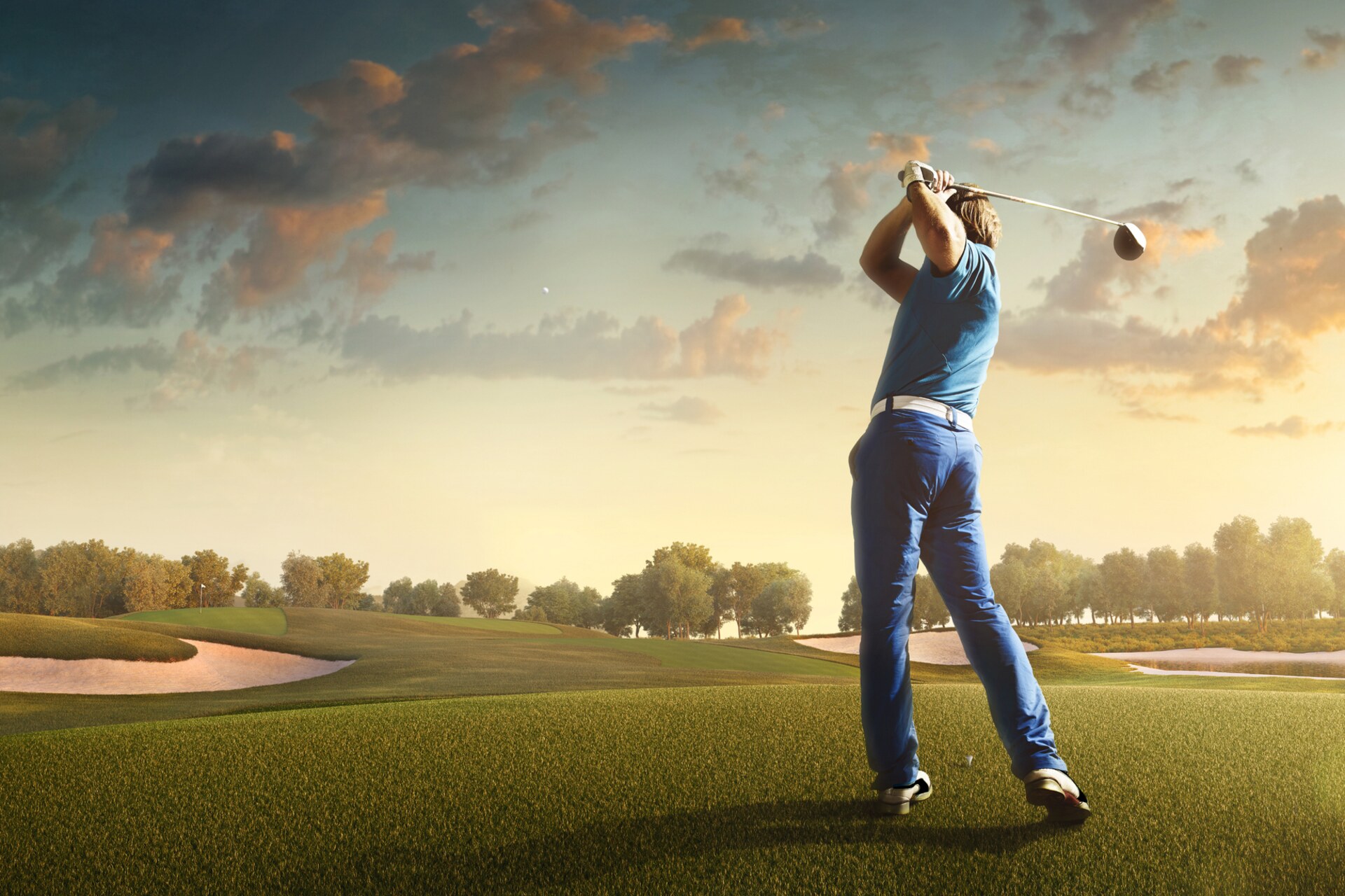 A golfer surveying a coastal green, with the fairway stretching ahead under bright sky.